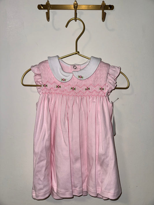 Pink dress on a hanger against a plain background