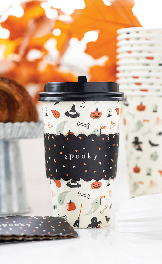 Halloween-themed cup with black lid and decorative pattern on a white surface. features pumpkins, witches hats, bones and brooms. 