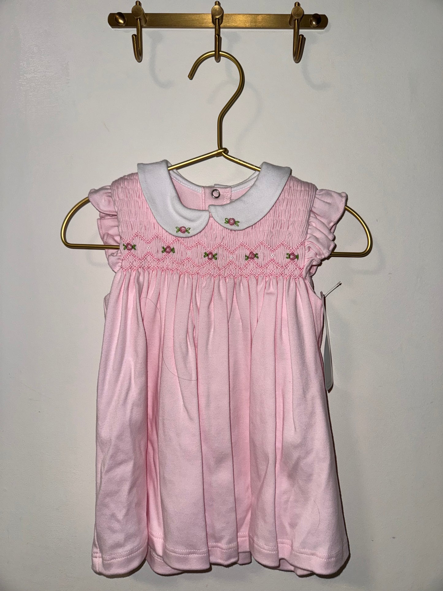 Pink dress on a hanger against a plain background