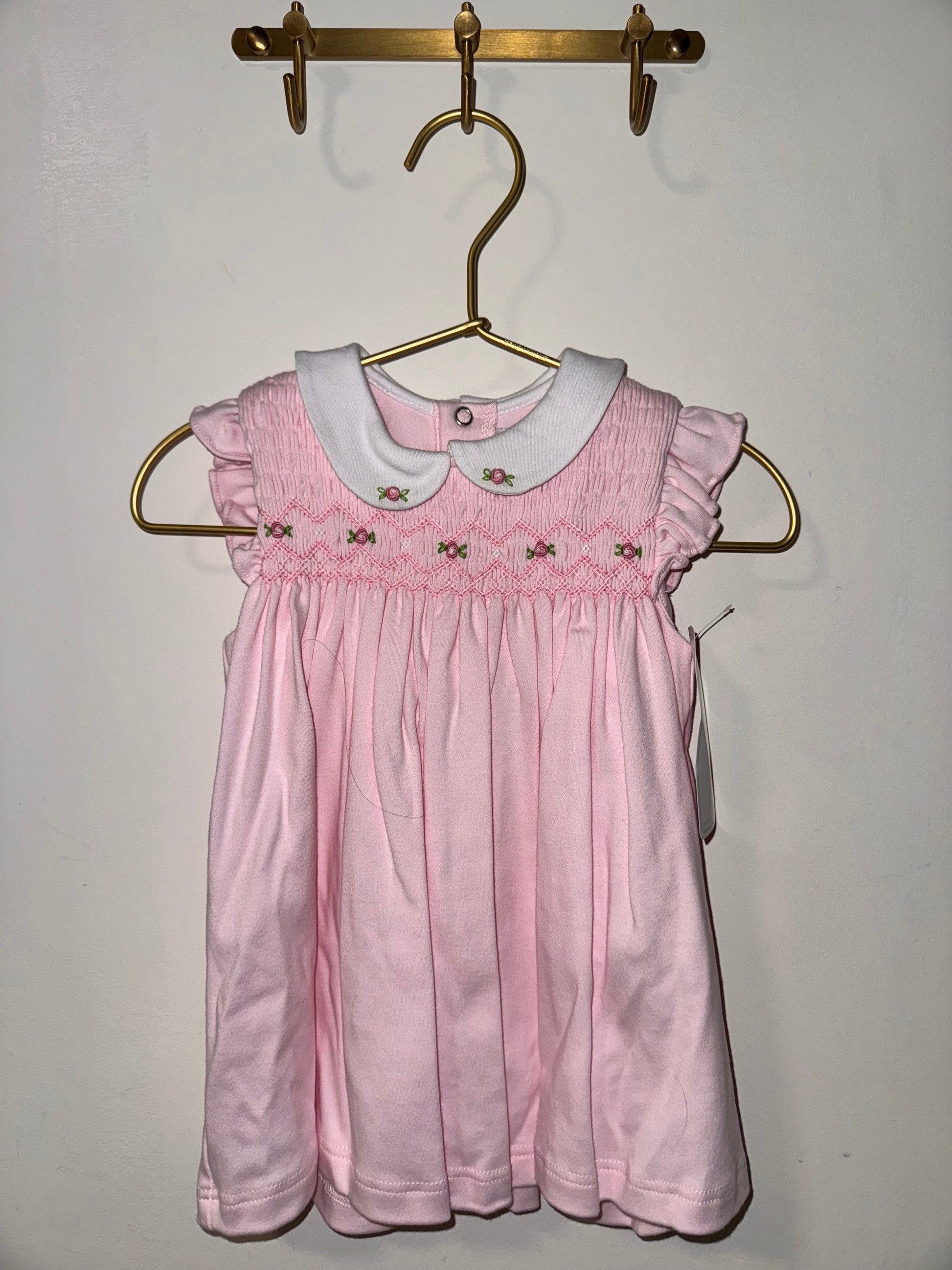Pink dress on a hanger against a plain background